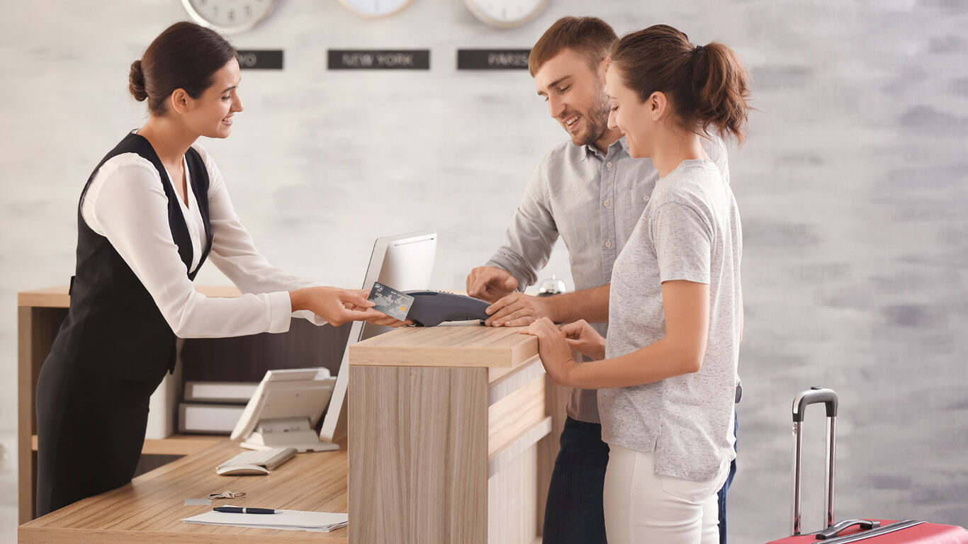 Front desk worker checking couple in stock image 
