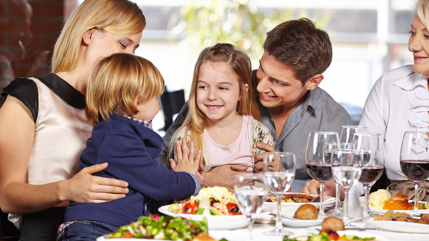 Family sitting at a restaurant table eating. 